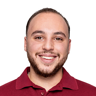 Ein lächelnder Mann in einem roten Hemd blickt freundlich in die Kamera.