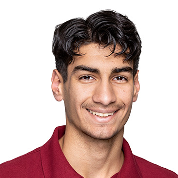 Ein junger Mann in einem weinroten Poloshirt lächelt freundlich in die Kamera.