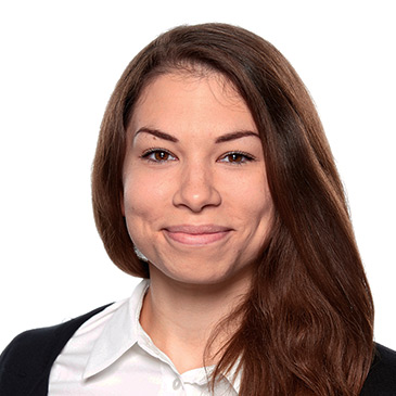 Eine Frau mit braunen Haaren lächelt freundlich vor einem weißen Hintergrund.