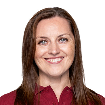 Eine Frau mit langen braunen Haaren lächelt freundlich in die Kamera und trägt ein rotes Hemd.